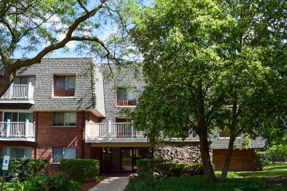 Front view of a multi-story apartment building with balconies and brick exterior.