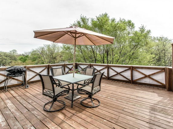Wooden rooftop deck with seating area and umbrella.