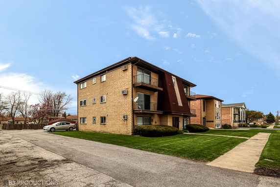Front view of a three-story brick apartment building with balconies.