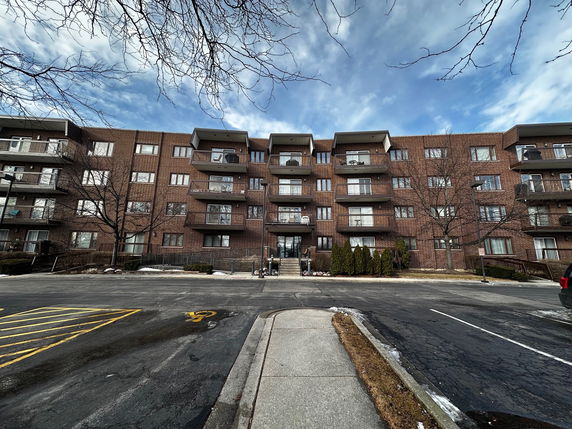 Front view of a multi-story brick apartment building with balconies.