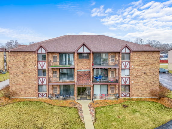 Front view of a three-story brick apartment building with balconies.
