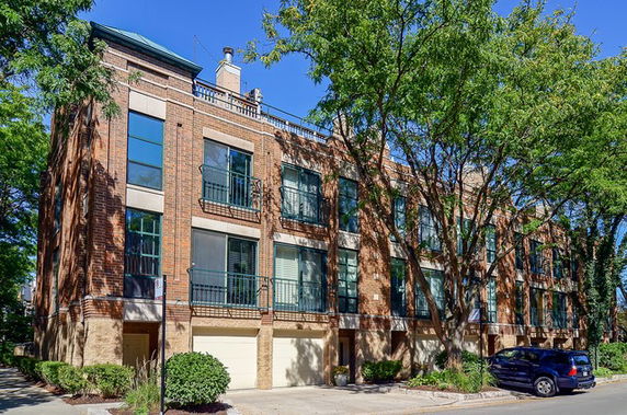 Front view of a multi-story brick building with large windows and a driveway.
