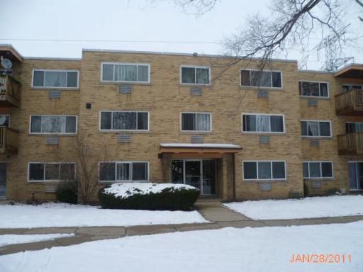 Front view of a three-story brick apartment building with multiple windows and balconies.