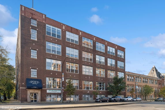 Front view of a multi-story brick building with large windows and commercial signage.