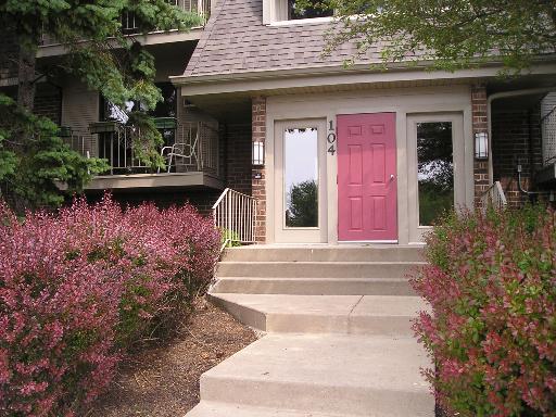Front view of a house with a red door and steps leading up to the entrance.