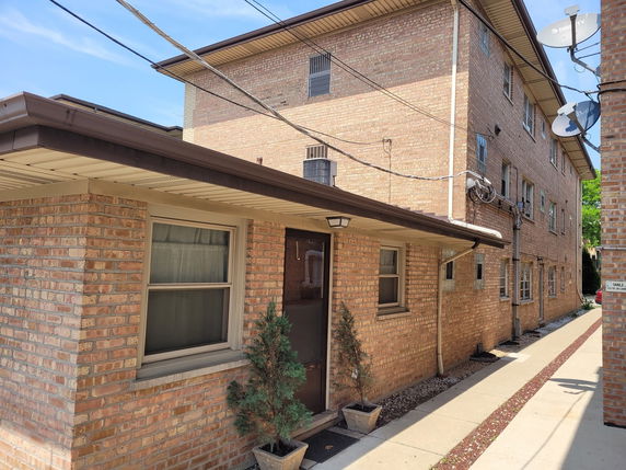 Front view of a multi-story brick building with multiple windows and a side entrance.
