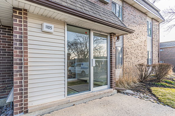 Front view of a building with brick and siding exterior and large glass doors.