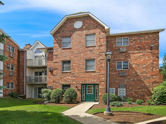 Front view of a multi-story brick apartment building with balconies.