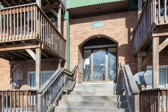 Front view of a brick building with wooden balconies and a central entrance.