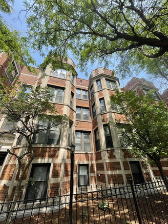 Front view of a multi-story brick building with large windows.