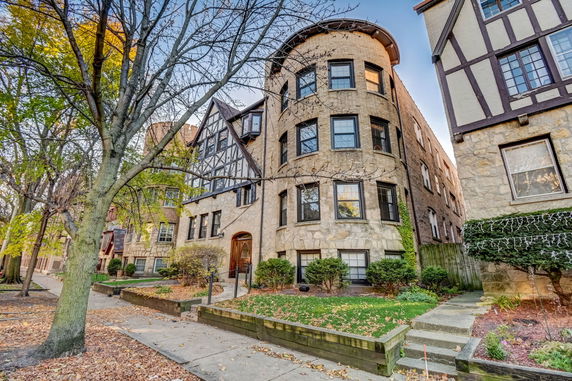 Front view of a multi-story building with a rounded corner and Tudor architectural elements.