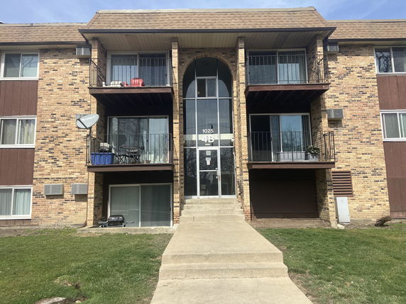 Front view of a multi-story apartment building with balconies.
