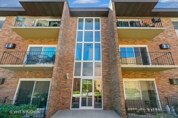 Front view of a multi-story brick condominium building with balconies.