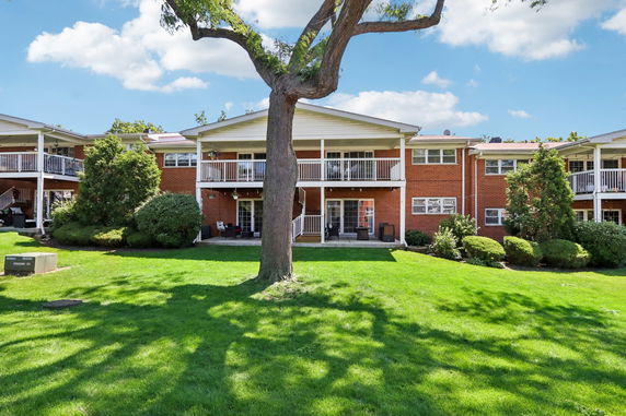 Front view of a two-story apartment building with balconies and a central lawn area.