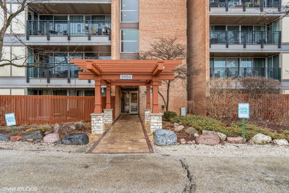 Front view of a multi-story building with balconies and brown brick facade.