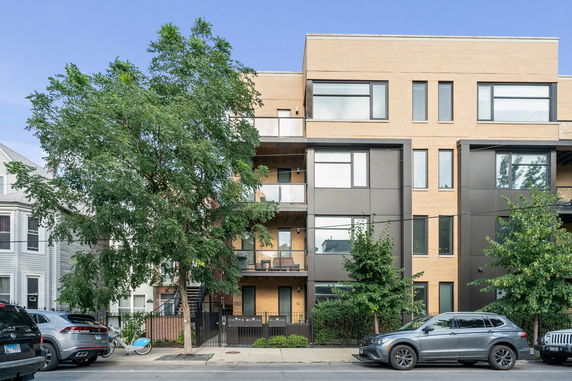 Front view of a modern multi-story apartment building with large windows and balconies.