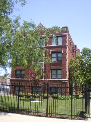 Front view of a multi-story brick apartment building with a gated entrance.