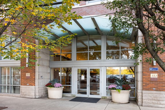 Front view of a building entrance with large glass doors and potted plants.