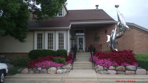 Front view of a house with a sculpture and landscaped garden.