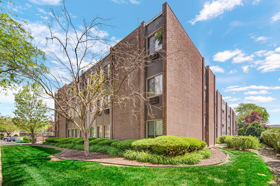 Front view of a multi-story brick building with large windows.