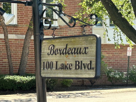 Front view of a brick building with a hanging sign.