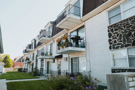 Front view of a multi-story residential building with balconies and brick exterior.