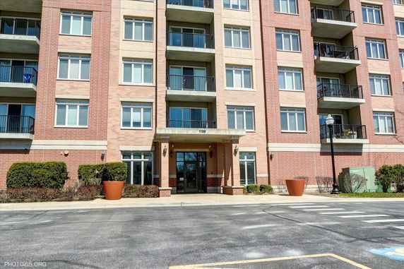 Front view of a multi-story brick apartment building with balconies.