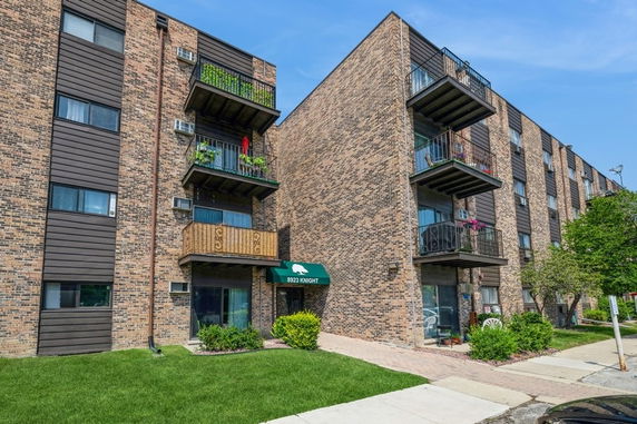Front view of a multi-story brick apartment building with balconies.
