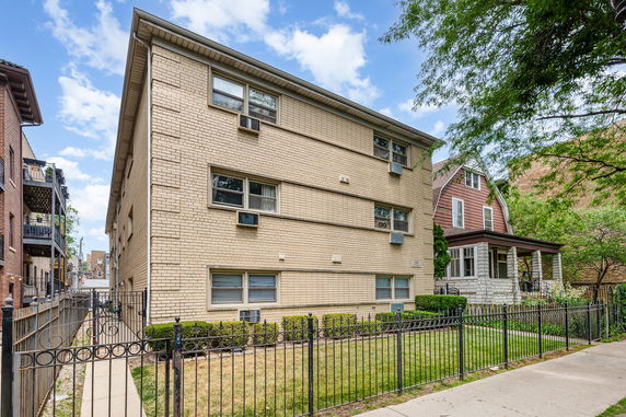 Front view of a beige brick apartment building with multiple floors.