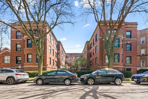 Front view of a multi-story red brick apartment building with large windows.