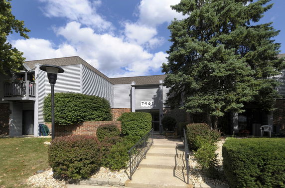 Front view of a two-story building with a sloped walkway and dark-colored roof.