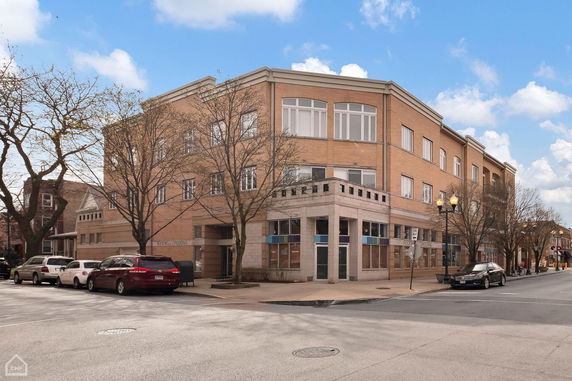 Front view of a multi-story brick building on a street corner.