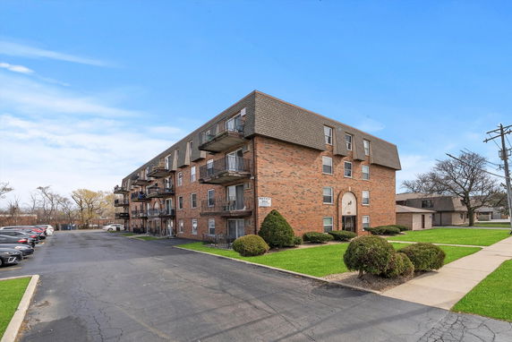 Front view of a multi-story brick apartment building with balconies.