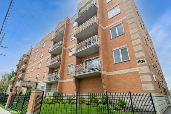 Front view of a multi-story brick apartment building with balconies.