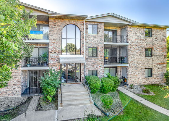 Front view of a multi-story brick apartment building with balconies.