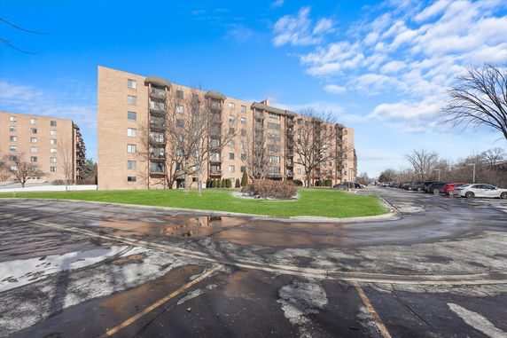 Front view of a multi-story apartment building with parking area.