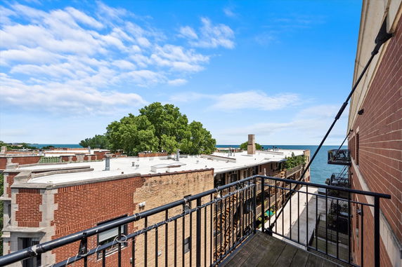 View from a balcony overlooking rooftops and a distant body of water.
