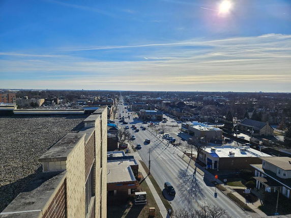 Panoramic view from a building overlooking a city street and surrounding areas under a clear sky.