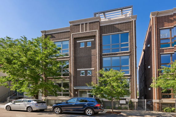 Front view of a modern multi-story building with large windows and brick exterior.