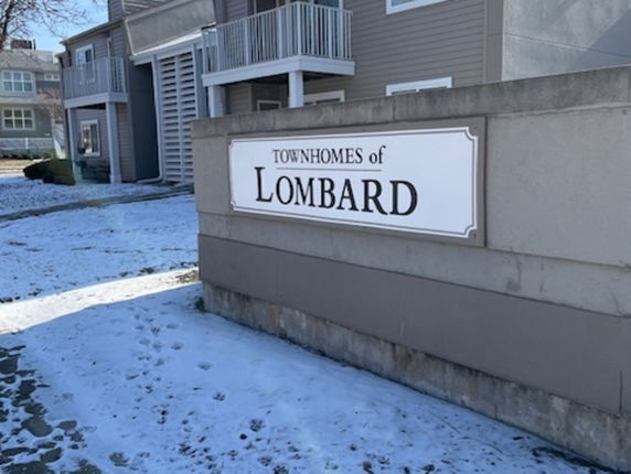 Front view of a townhouse complex with balconies and a sign indicating 'Townhomes of Lombard'.