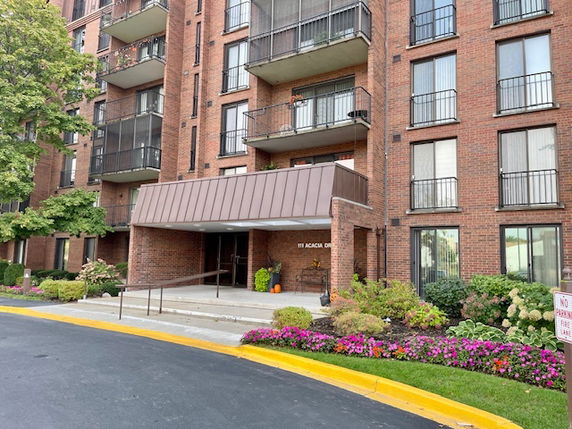 Front view of a multi-story brick building with balconies and a covered entrance.
