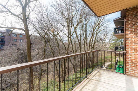 View from a building balcony overlooking trees and nearby apartment buildings.