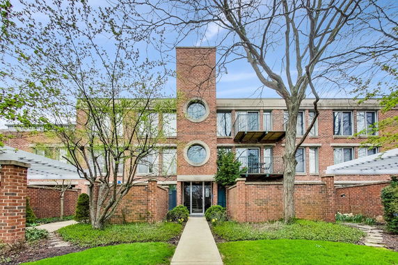 Front view of a multi-story brick building with circular windows and balconies.