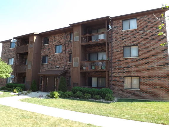 Front view of a multi-story brick apartment building with balconies.