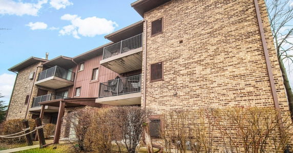Front view of a multi-story building with balconies and brick exterior.