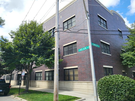 Front view of a multi-story brick building on a street corner.
