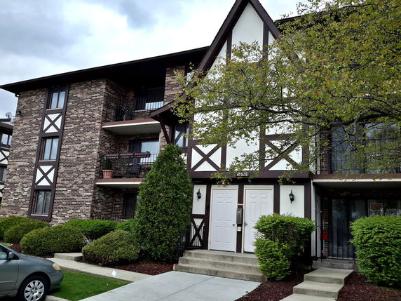 Front view of a multi-story building with two entrances and balconies.