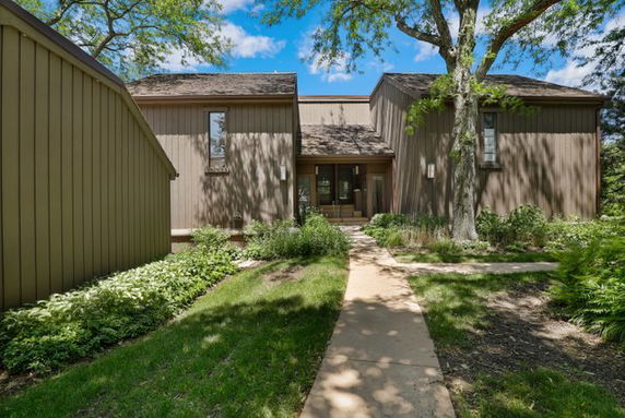 Front view of a modern two-story house with a wooden exterior and a central entrance.