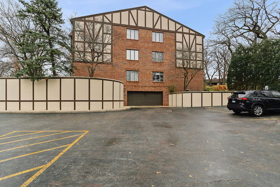 Parking area in front of a multi-story brick building with decorative paneling.