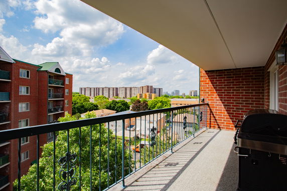 Balcony view of surrounding areas with apartment buildings and trees.